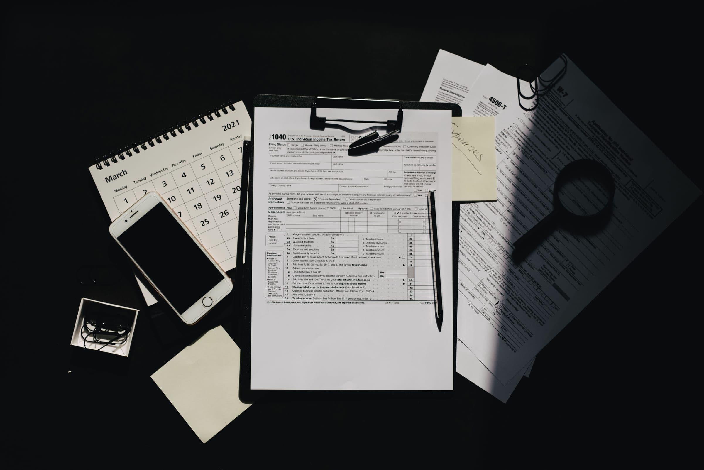Tax forms, calendar, and documents on a dark desk